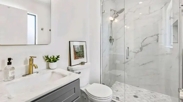 Laguna Niguel bathroom remodel with a gray vanity, brass faucet and a marble-look walk-in shower with frameless glass